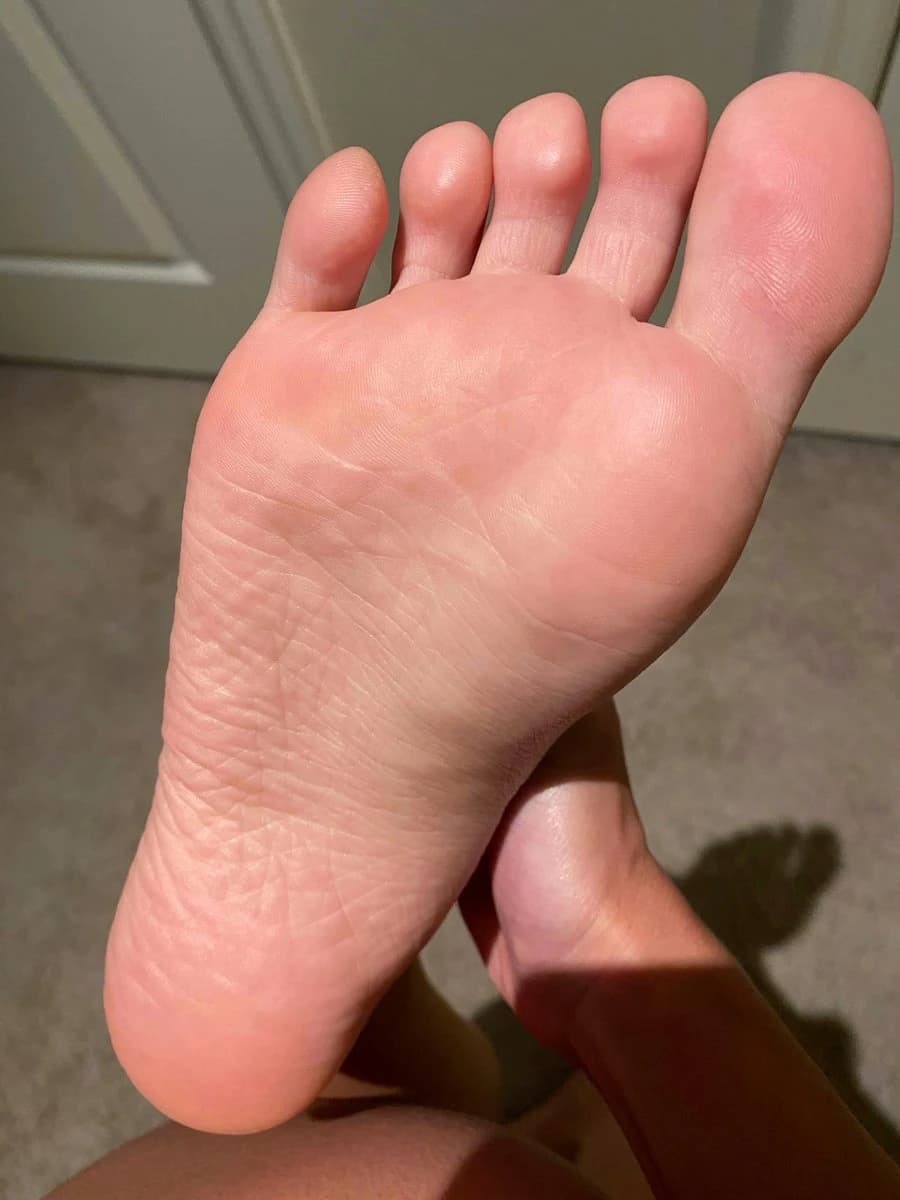 Beautiful toes with bright nail polish resting by the pool, sunny day, playful foot fetish shot